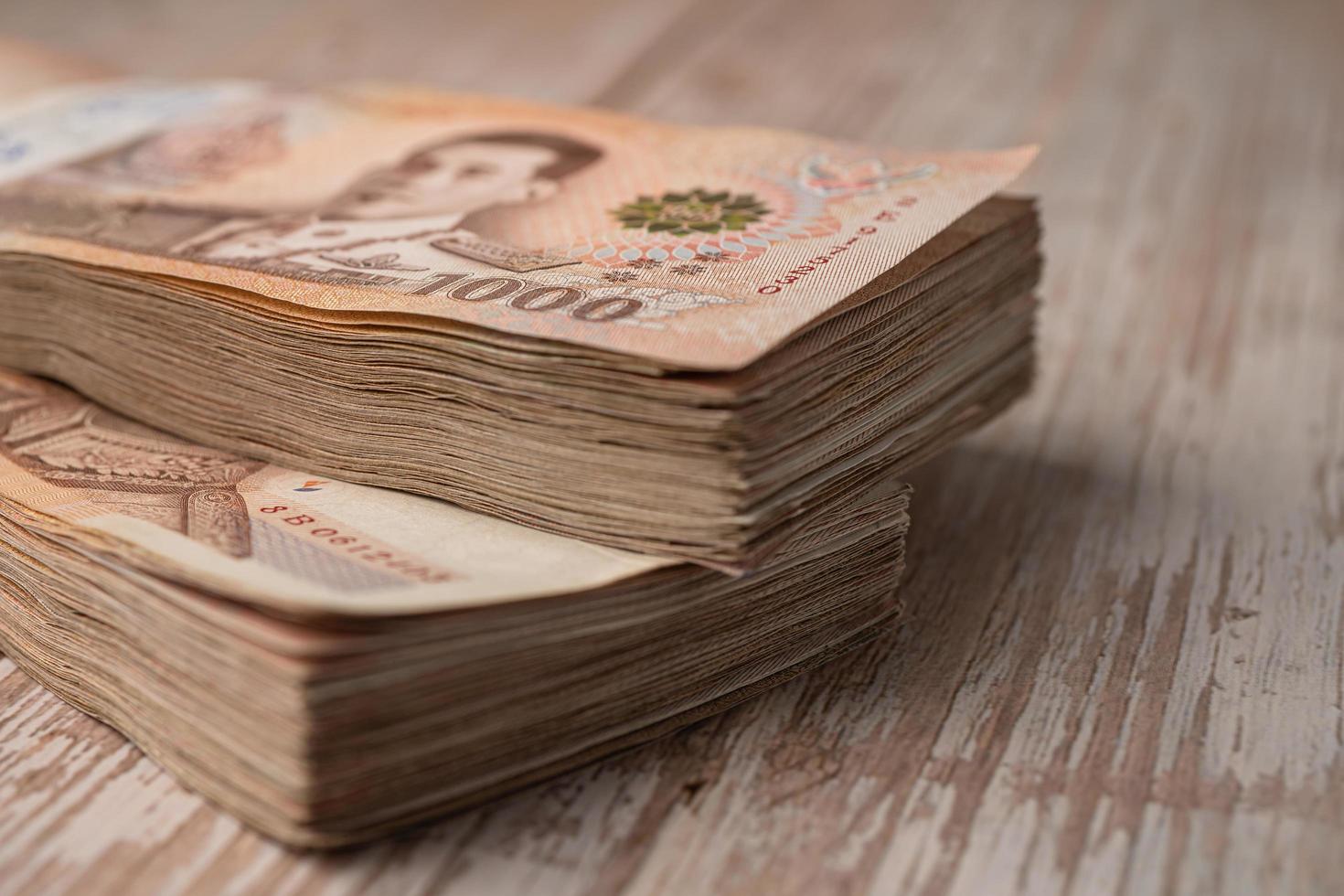 Stack of Thai baht banknotes on wooden background, business saving finance investment concept. photo