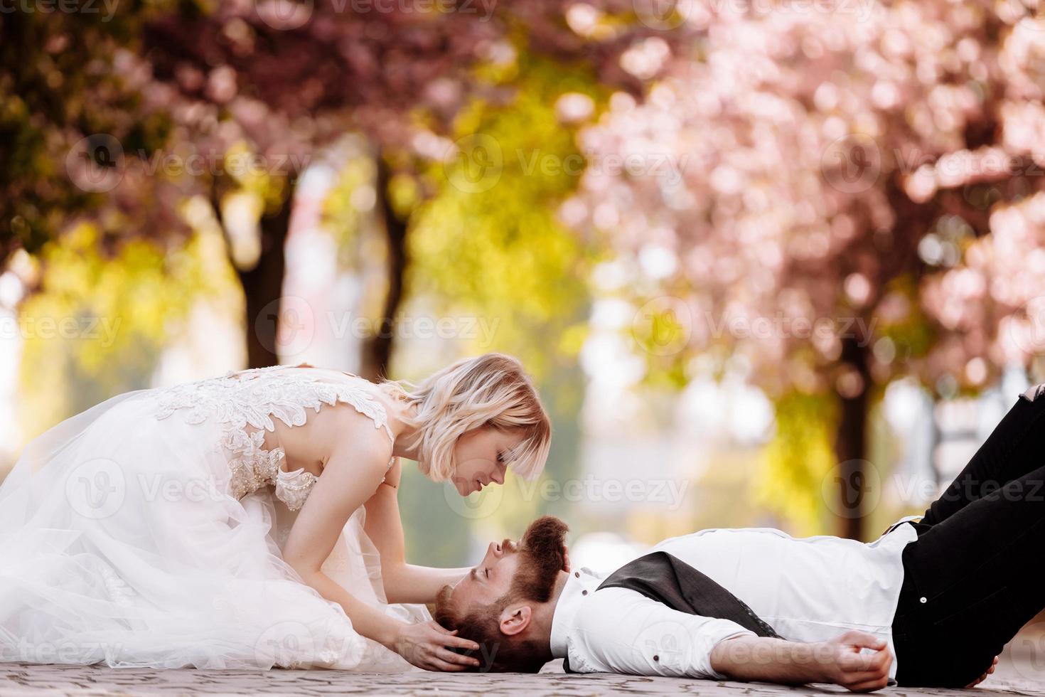 stylish couple lying on the ground in old town in spring. couple having fun together on urban background. couple enjoying spring. photo