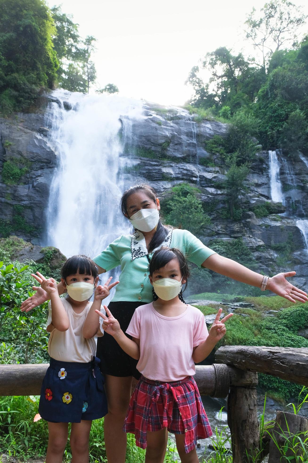 familia de turistas asiáticos de pie cerca de la cascada de wachirathan  mirando a la cámara y sonriendo en el parque nacional de inthanon, chiang  mai, tailandia. 8090698 Foto de stock en