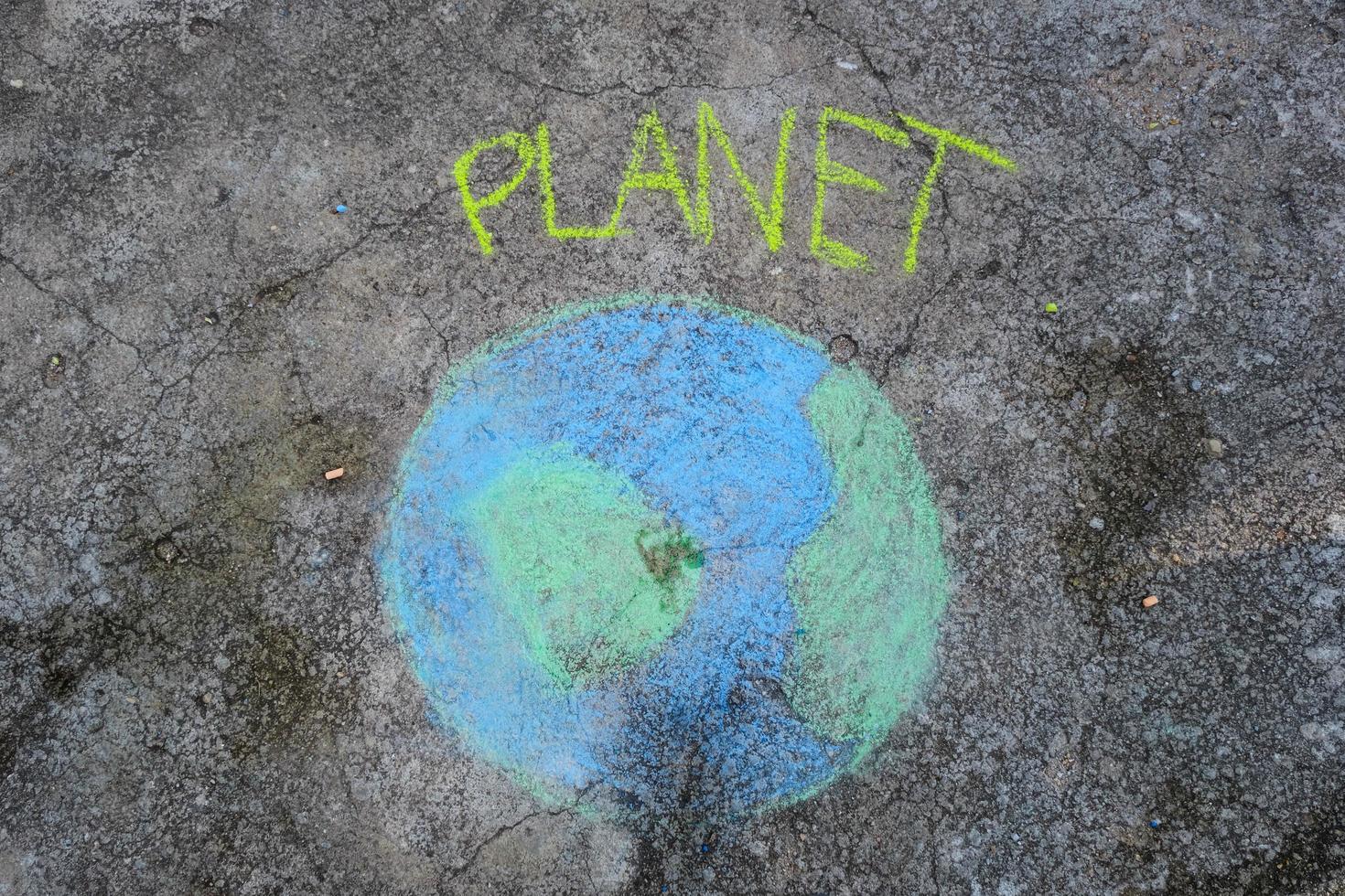 Beautiful world drawing with chalk with Planet text on asphalt. Concepts of world environment day and peace day. photo