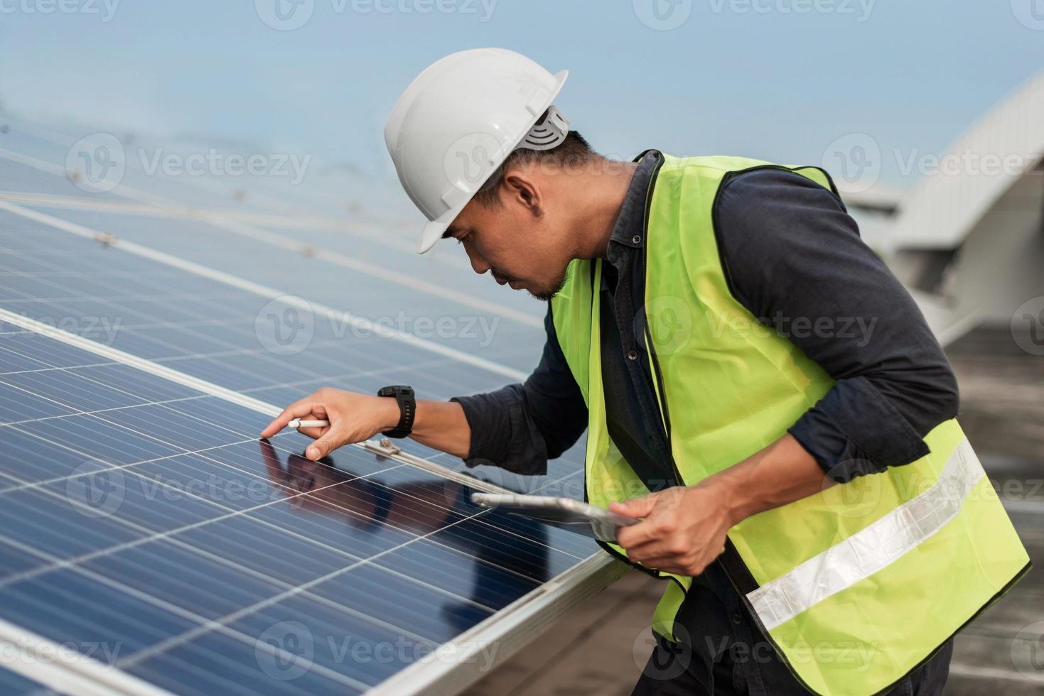 hombre ingeniero comprobando la energía de los paneles solares con tableta. revisión técnica y servicios de paneles solares fotovoltaicos. concepto de energía sostenible. foto