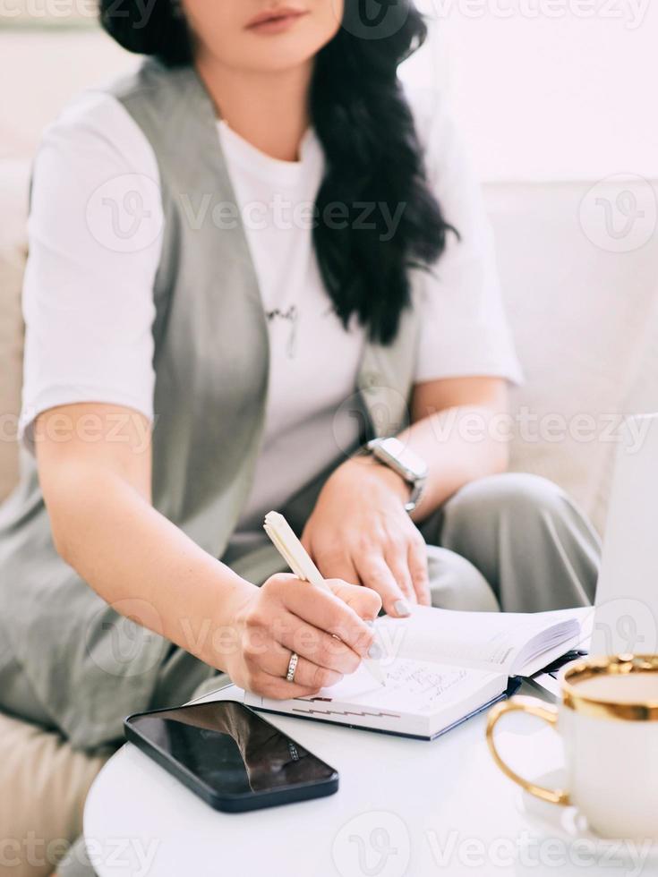 woman sitting on the sofa and making notes in her notebook. Business, analytics, education photo