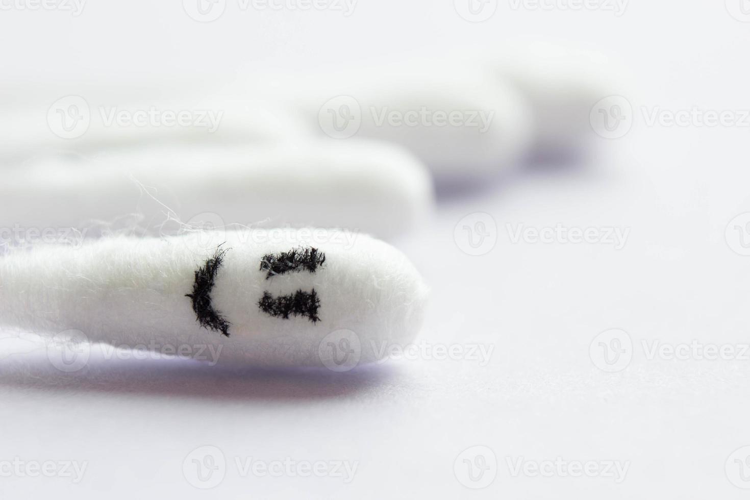 Close-up of cotton swabs with a smiling emoticon on a cotton swab in the foreground. Happiness concept photo