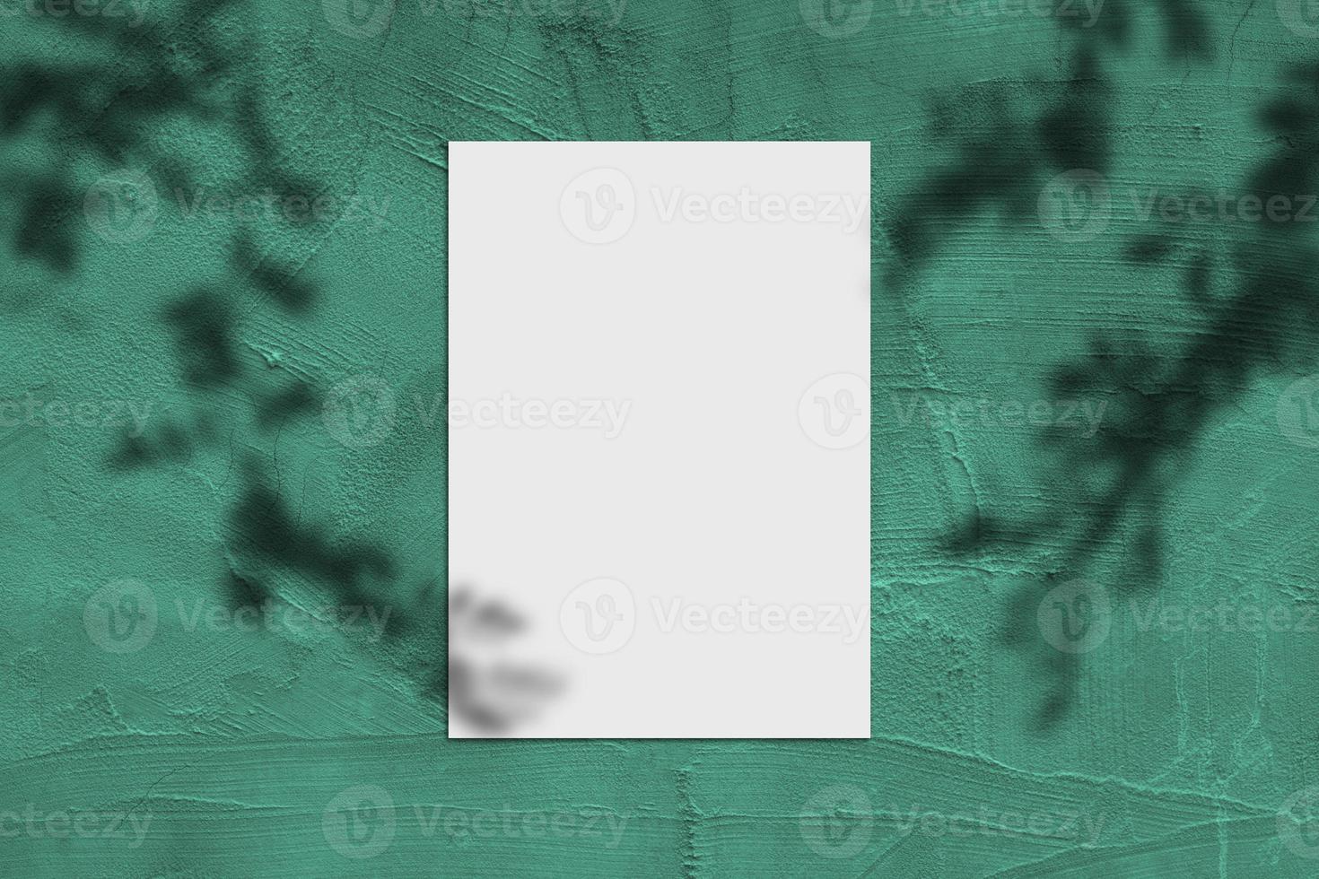 Blank white vertical rectangle poster mockup with light shadow on green concrete wall background. photo