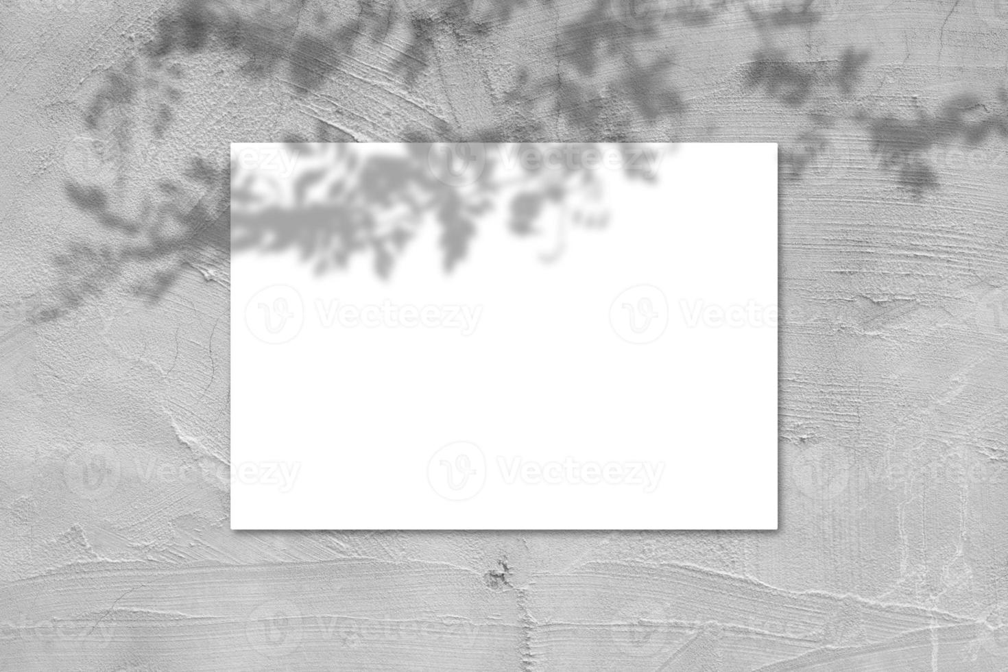 Empty white horizontal rectangular poster mockup with light shadow on gray concrete wall background. photo