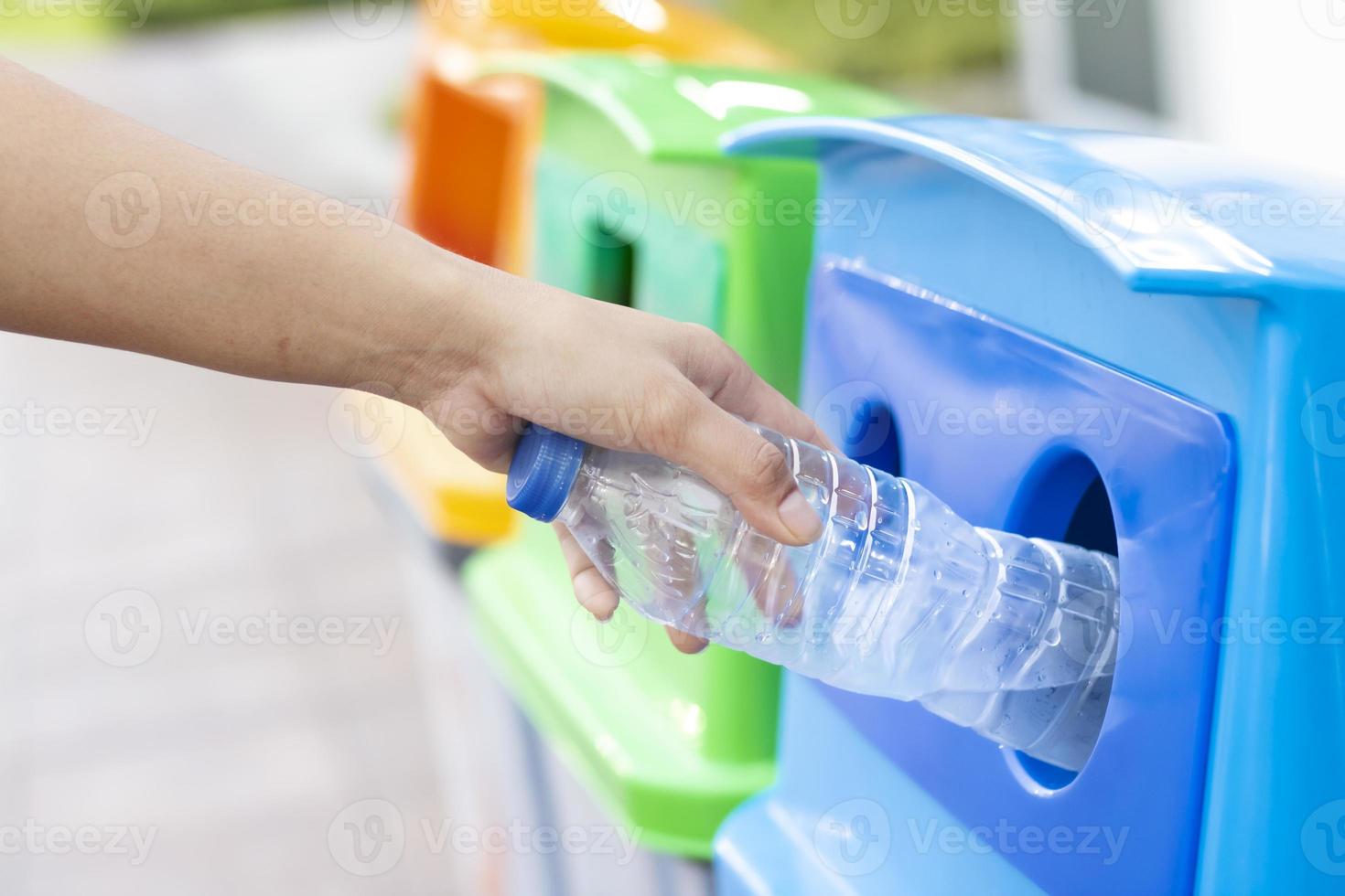 la gente está tirando botellas de plástico vacías a los contenedores de reciclaje. foto