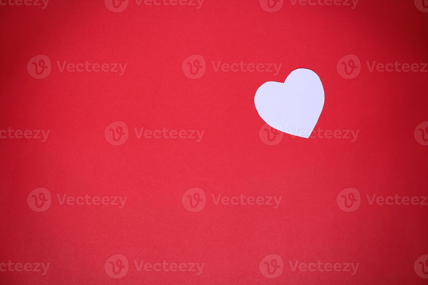 White heart-shaped paper on a red background with the concept Valentines Day photo