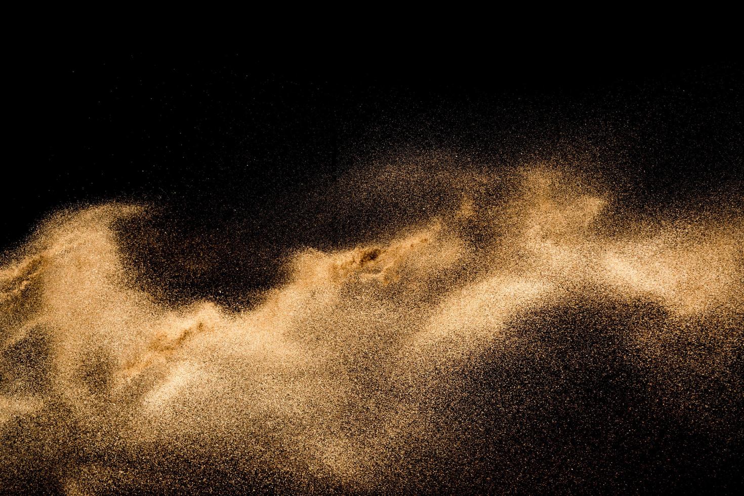 Dry river sand explosion. Golden colored sand splash agianst dark background. photo