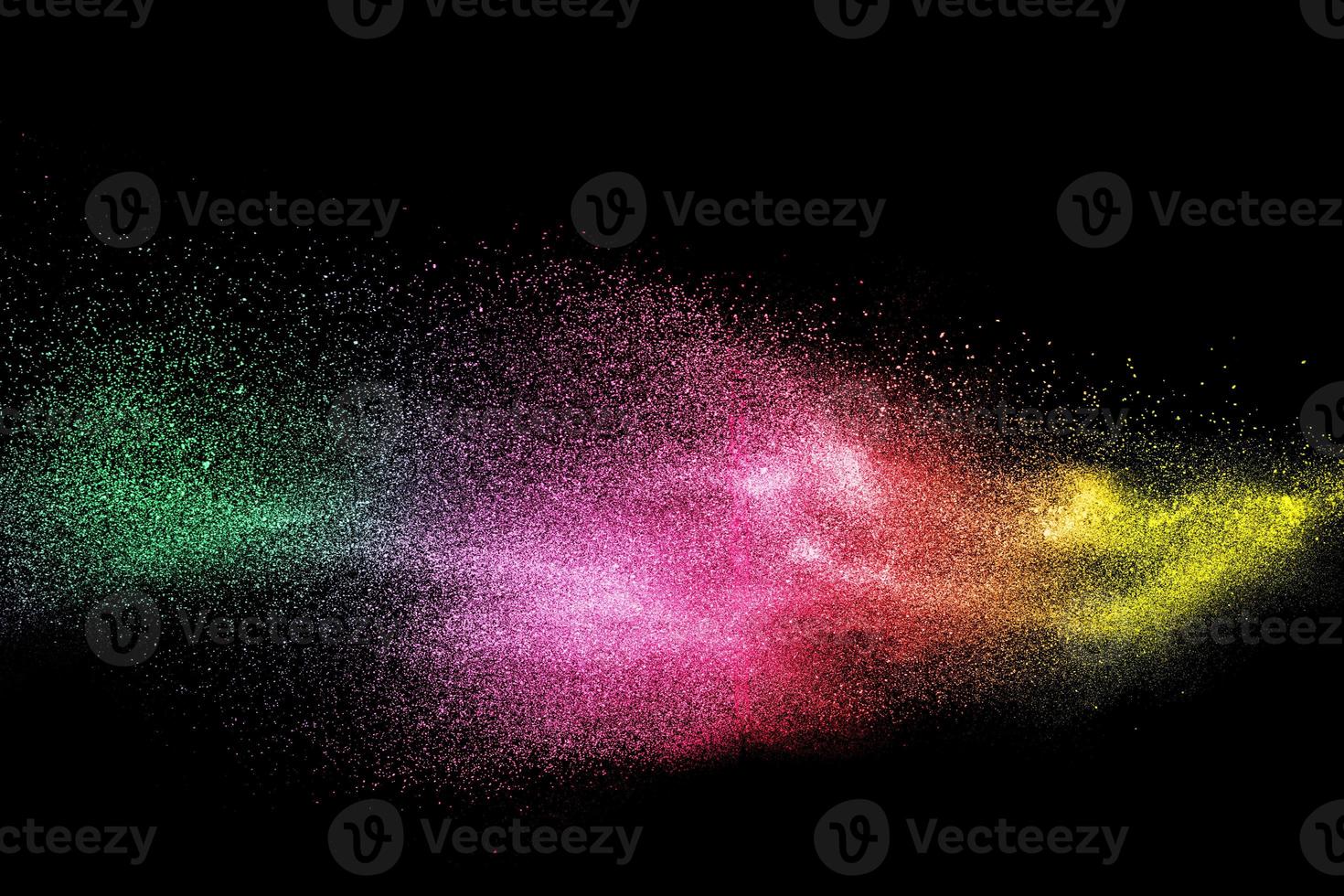 Green pink and yellow dust particles explosion on black background. Color powder dust splash. photo