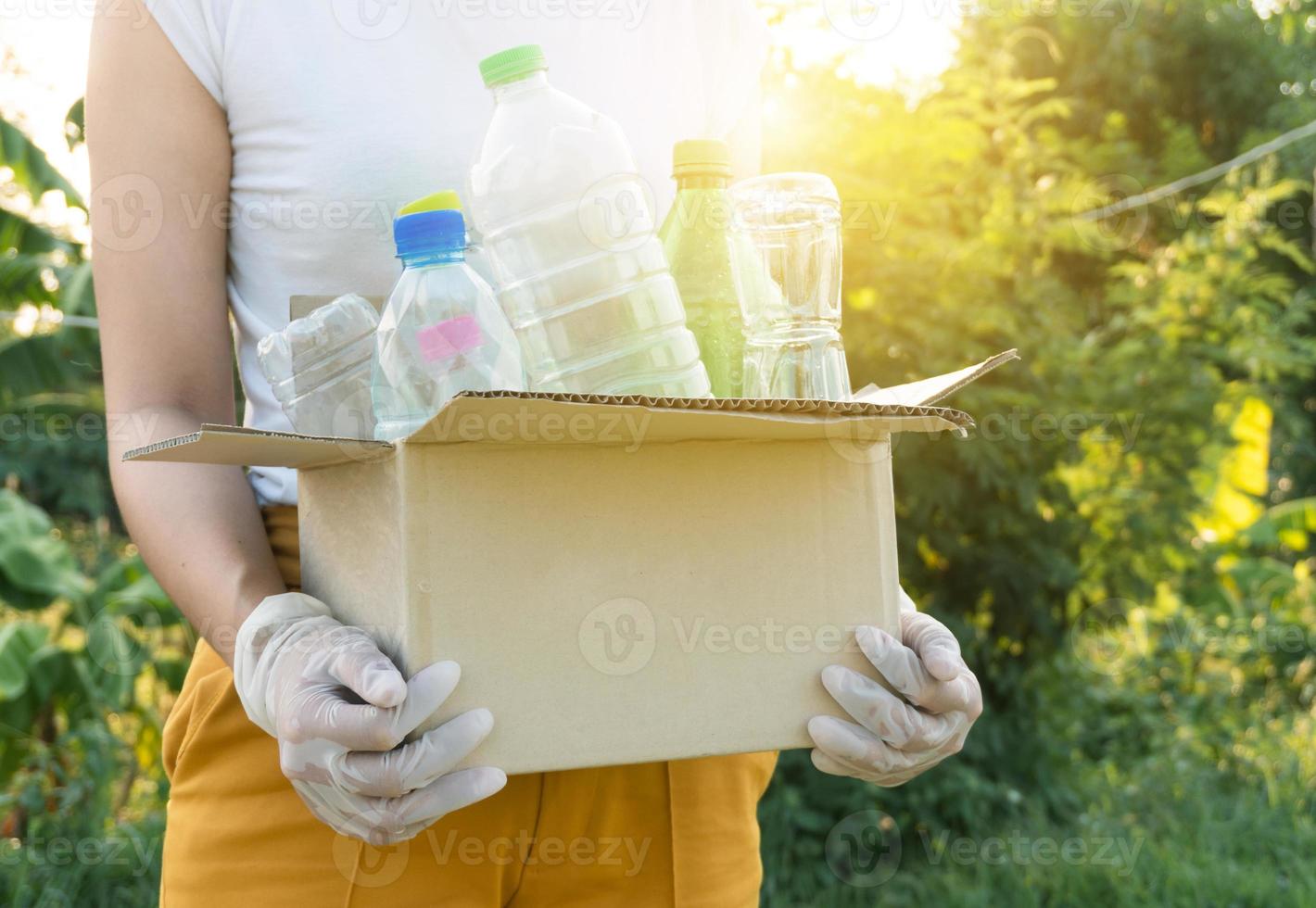 woman picking up garbage plastic bottles into a box for recycling concept photo