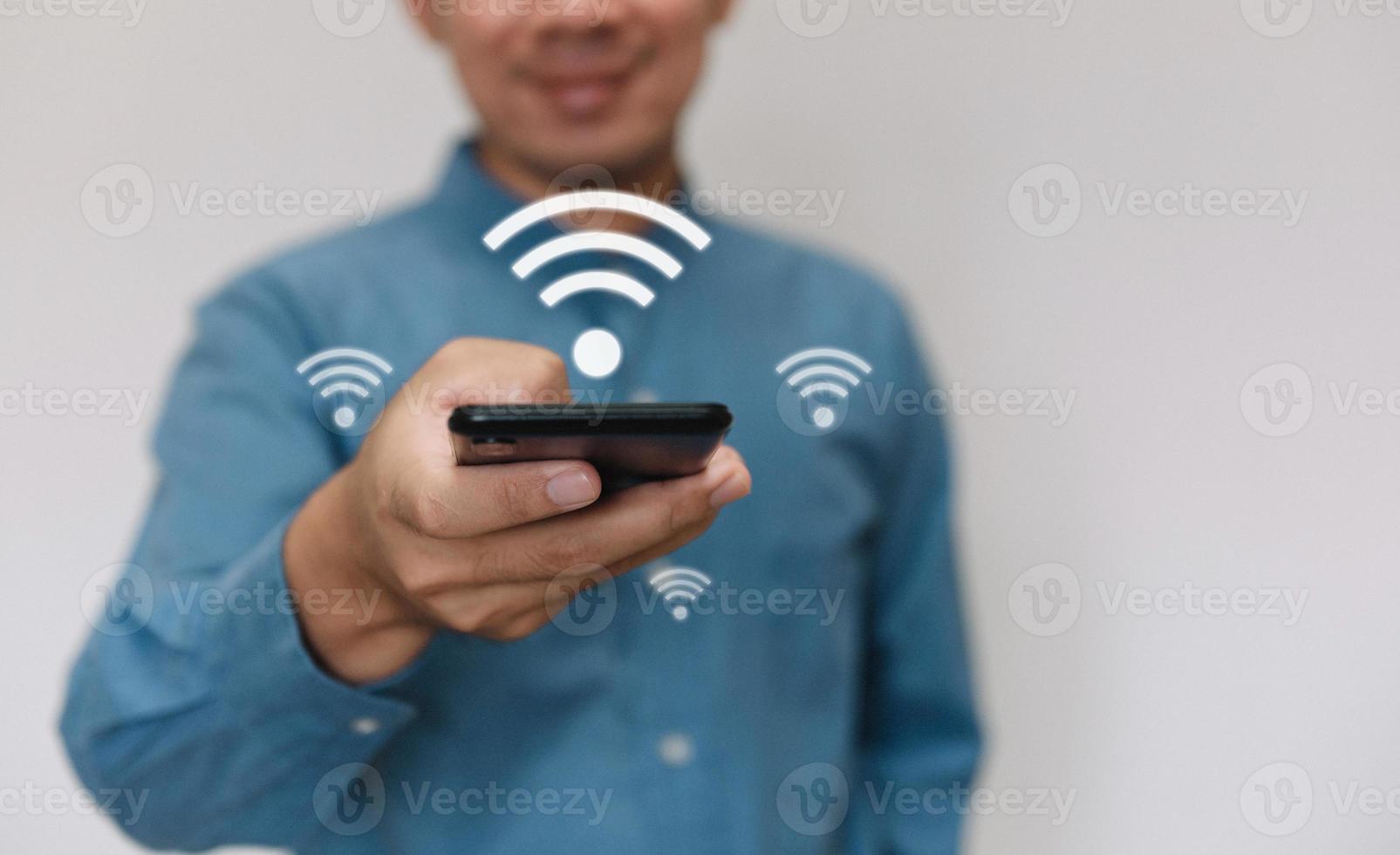 joven guapo con una camisa azul claro, use un teléfono inteligente conectado a la tecnología wi-fi para usar la función de hogar inteligente. negocio de tecnología y concepto de estilo de vida moderno. foto