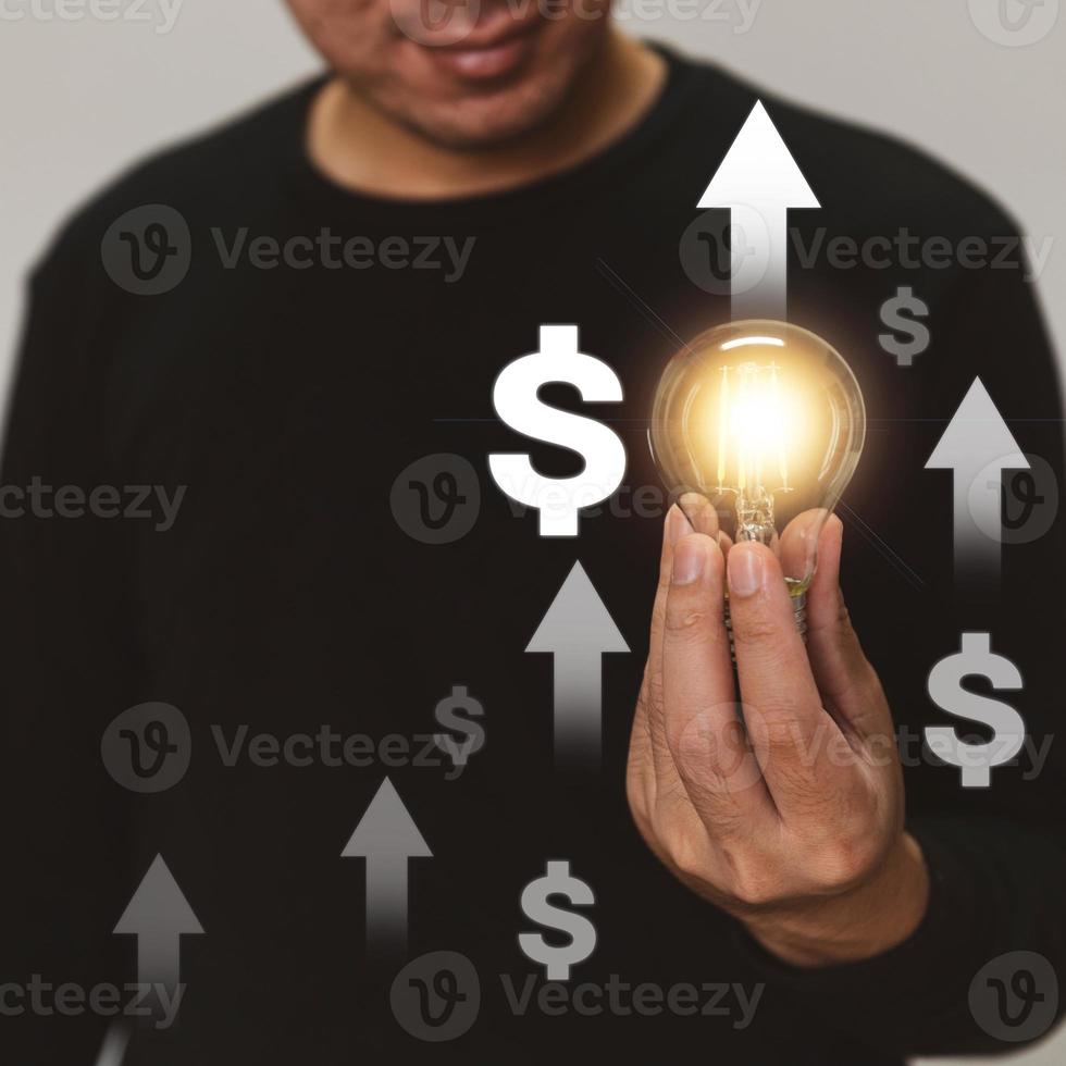 Hand holding a light bulb rises up with investment arrow for business growth and profit increase concept. photo