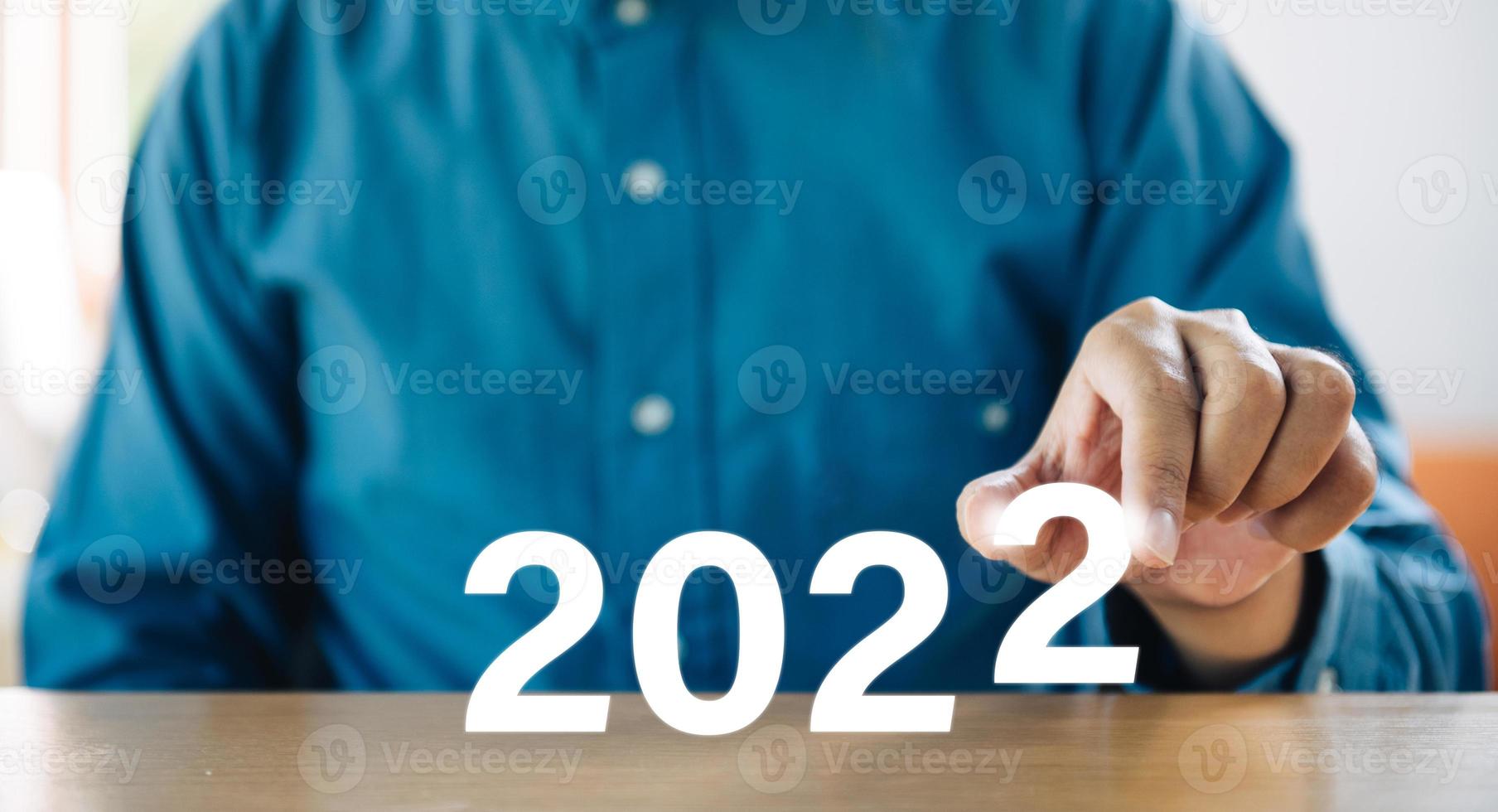Successful international financial investment concept with business person holding glowing in 2022 sign. new business year changing and start new target concept. photo