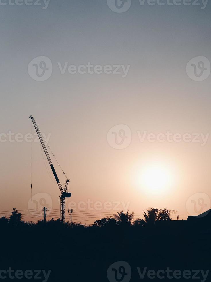 Fondo industrial abstracto con siluetas de grúas de construcción sobre el increíble cielo del atardecer foto