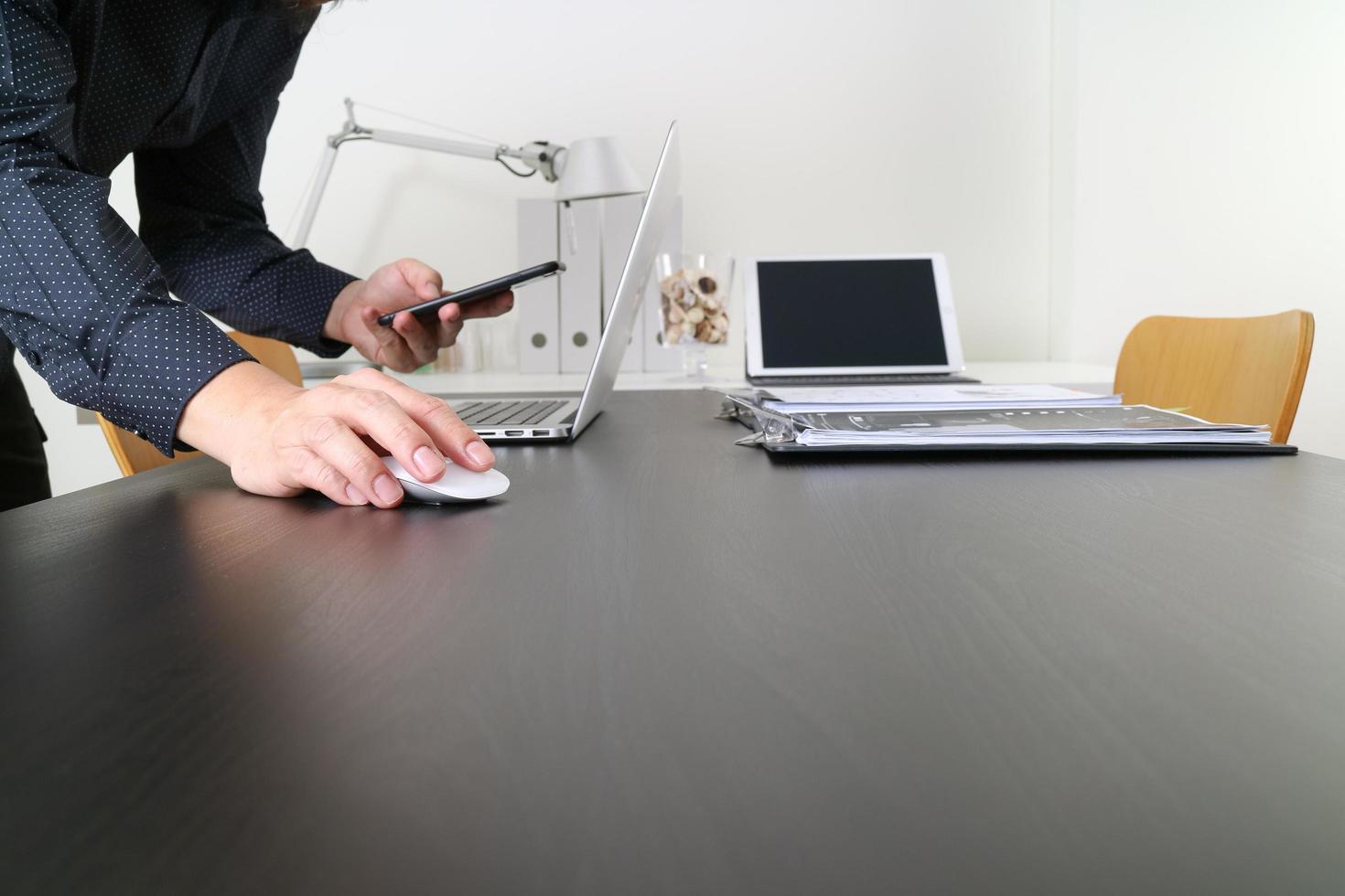 hombre de negocios o diseñador usando mouse y teléfono inteligente con computadora portátil y tableta digital en la oficina moderna foto