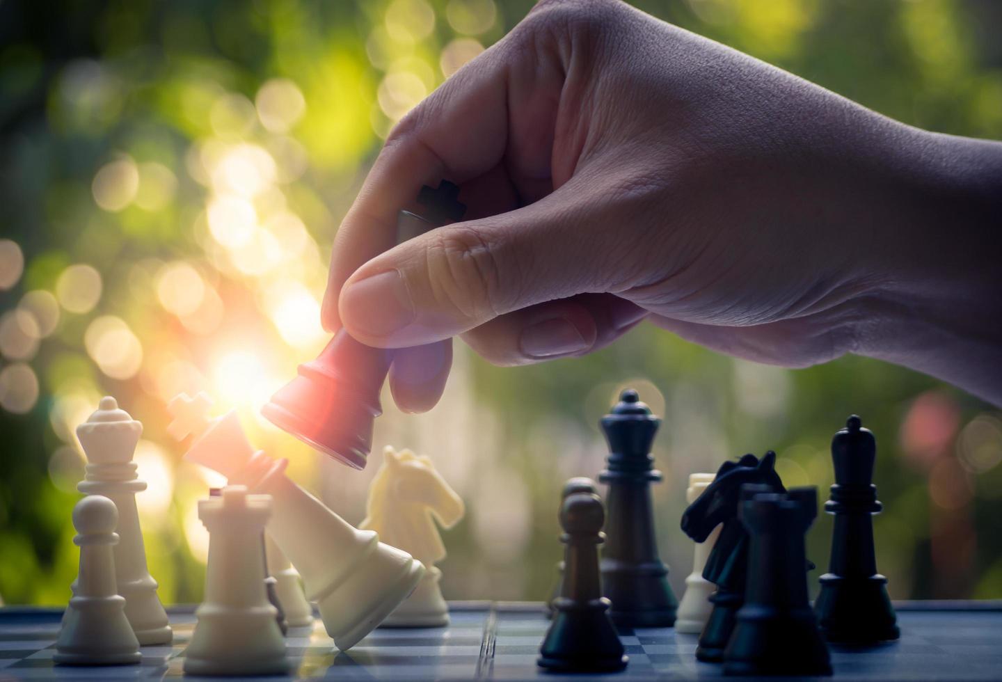 Hand holding Black king attack white king of chess battle on board. Black king are leader to fight with teamwork to victory. Leader,strategy and checkmate concept for success.Competition and defeating photo