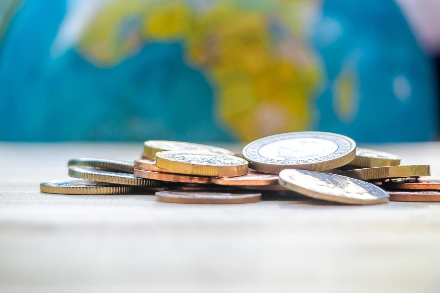 Coins stack on wood table in front of globe model. Concept for loan, property ladder, financial, mortgage, real estate investment, taxes and bonus. photo