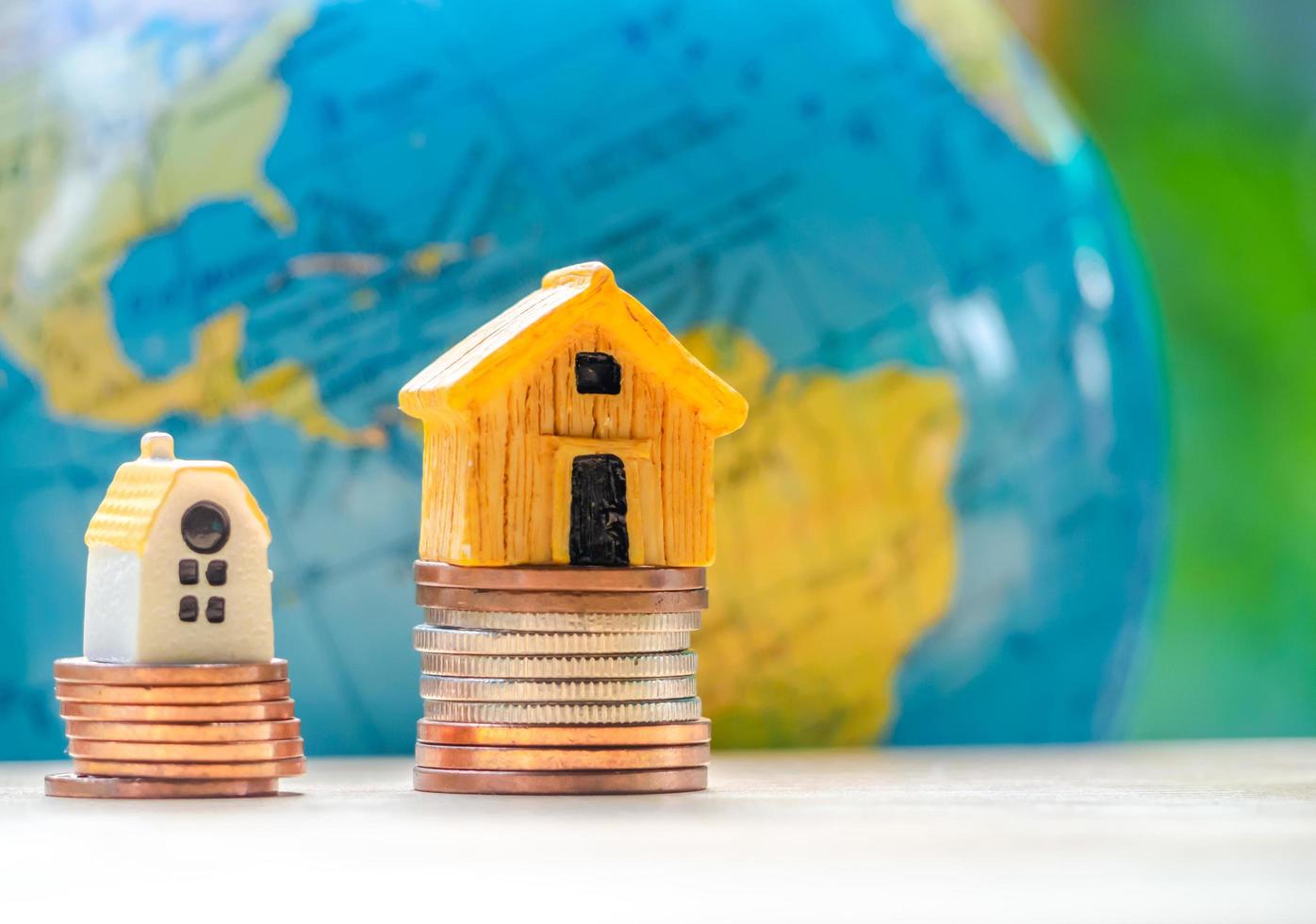 House or Home model with coins stack in front of globe model. Concept for loan, property ladder, financial, mortgage, real estate investment, taxes and bonus. Communication concept. photo