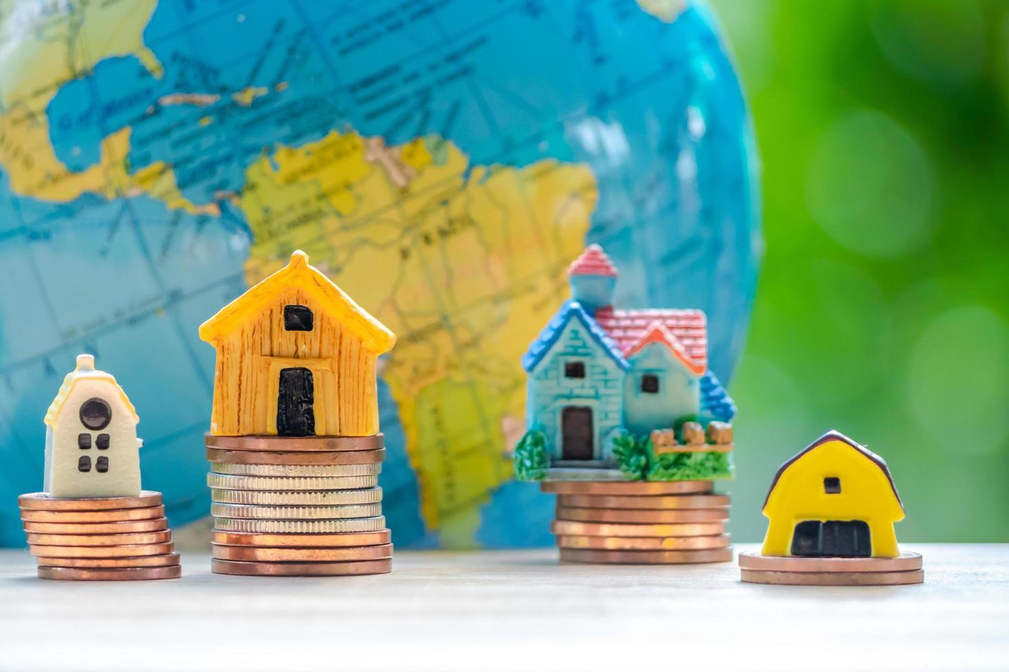 House or Home model with coins stack in front of globe model. Concept for loan, property ladder, financial, mortgage, real estate investment, taxes and bonus. Communication concept. photo