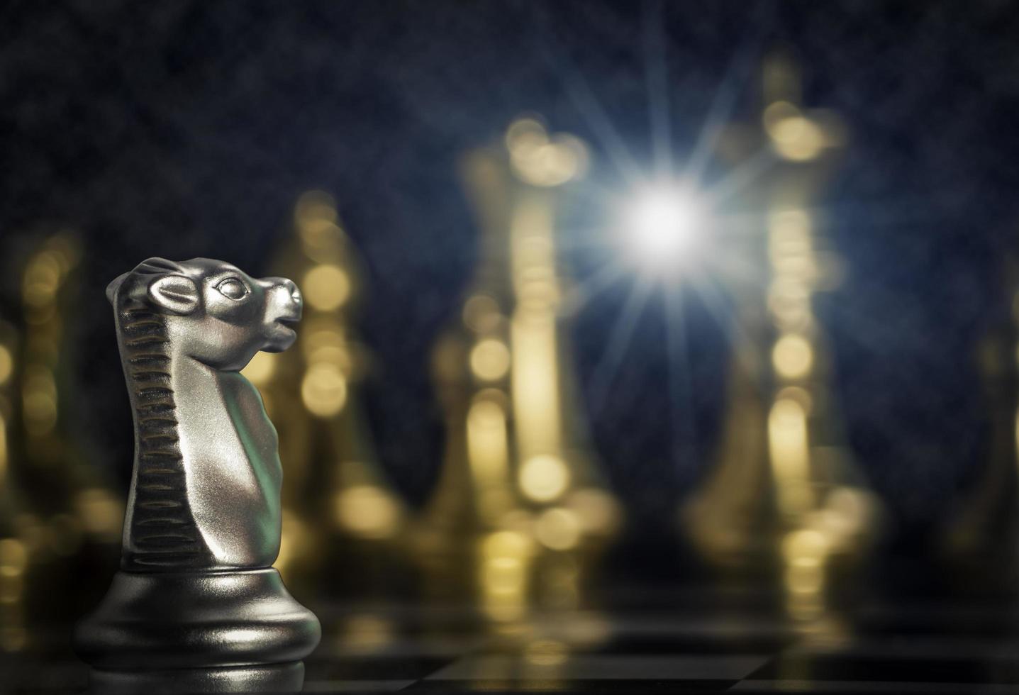 Silver knight chess pieces facing in front gold chess on board with flare light to successfully in the competition. Management or leadership strategy and teamwork concept. photo