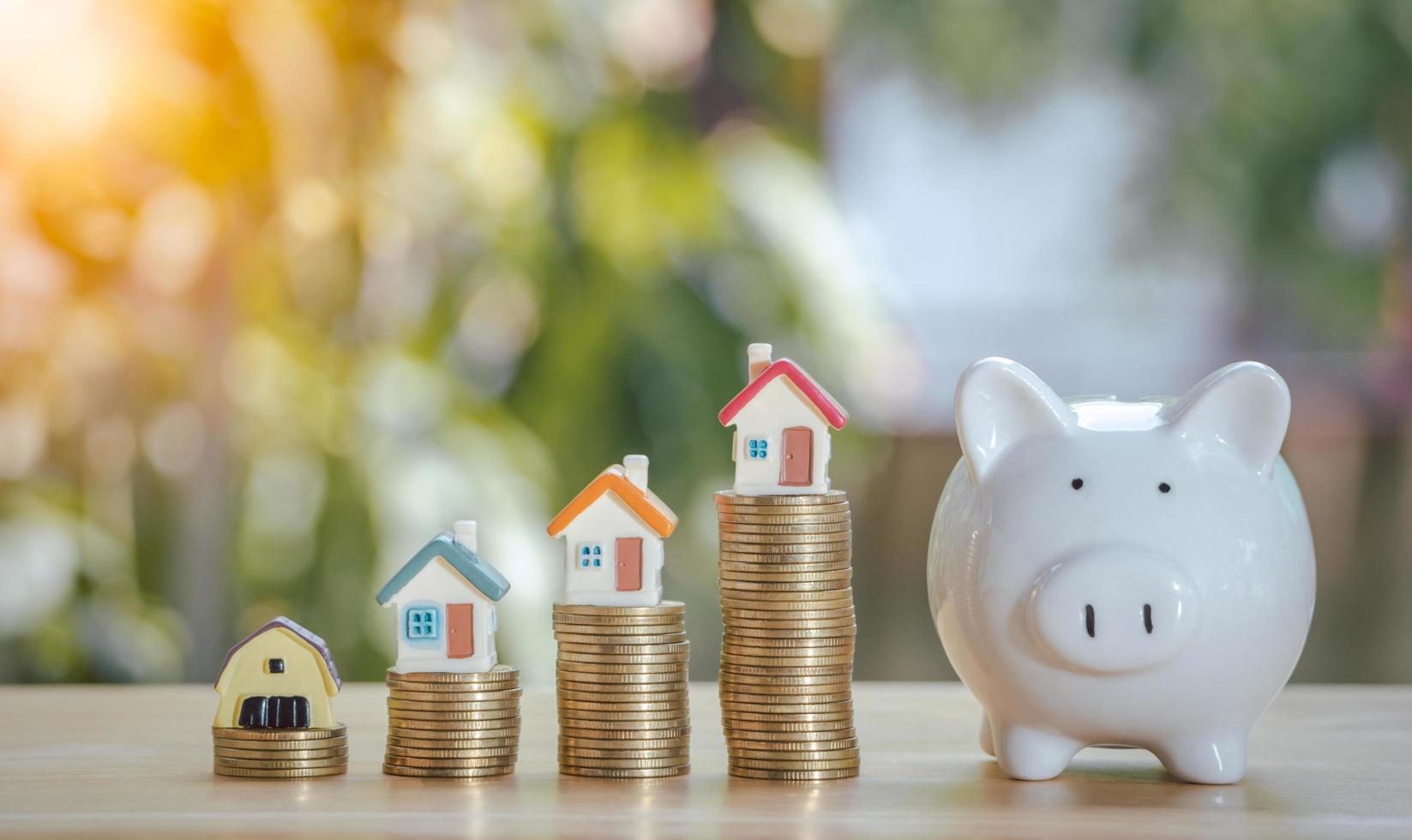 Coins stack 4 rows of gold coins and a white piggy bank placed on a wooden table to save money invest for future. Concept for loan, property ladder, financial, real estate investment, taxes and bonus. photo