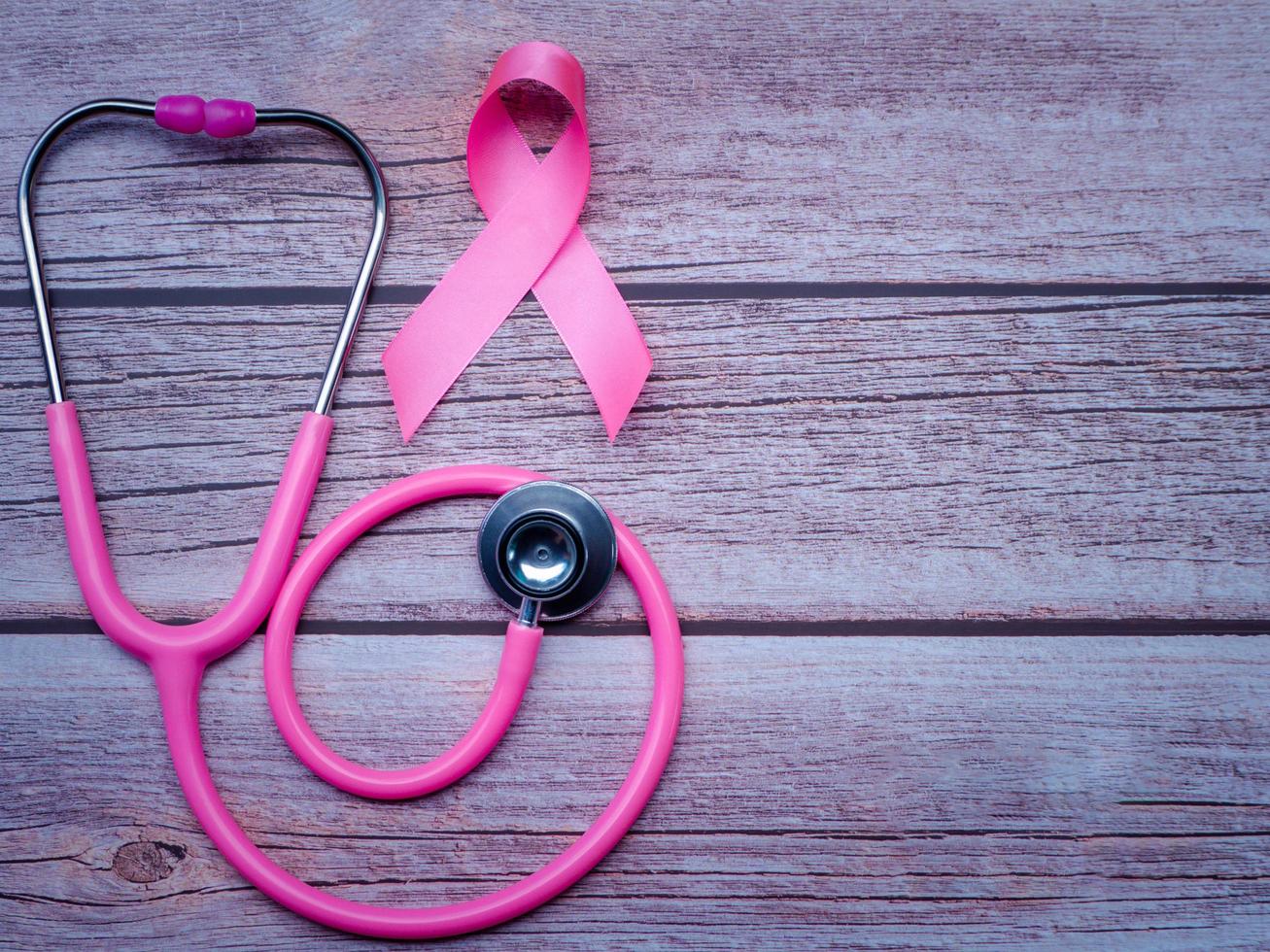 cinta rosa y estetoscopio en estilo vintage de mesa de madera. símbolo de cáncer de mama, concepto de atención médica foto