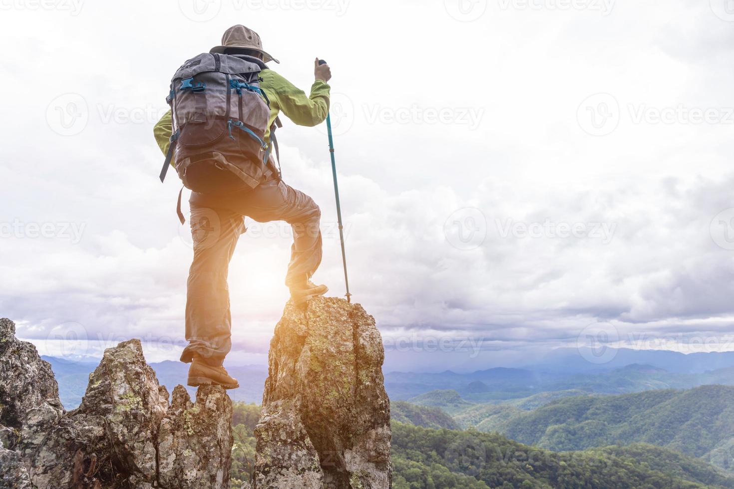 los escaladores activos disfrutan de la vista.la mochilera con mochila y muletas disfruta del sol en la montaña, copie el espacio. foto