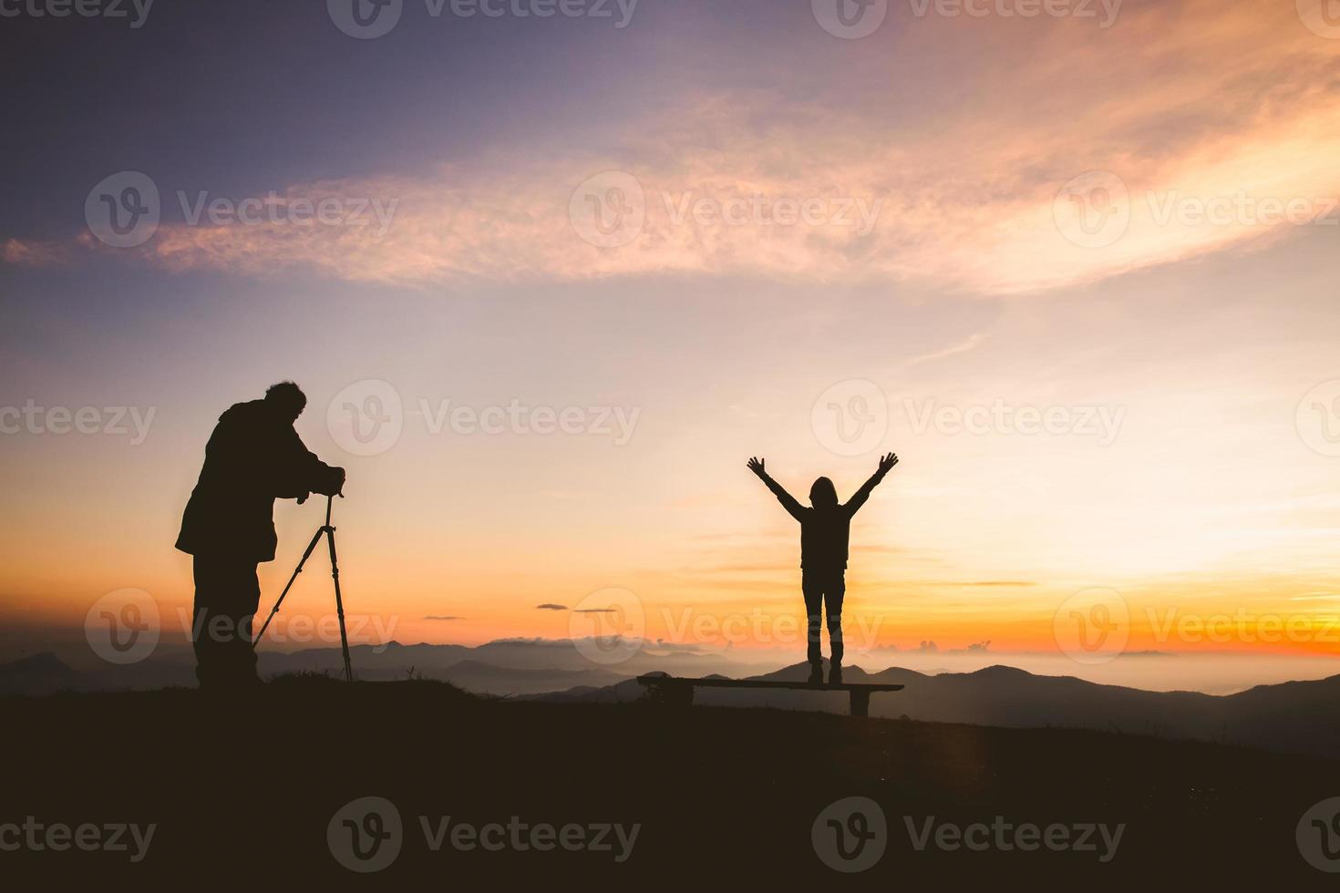 silueta de fotógrafo tomando fotos con modelo en la montaña al atardecer, fotografía profesional de bodas