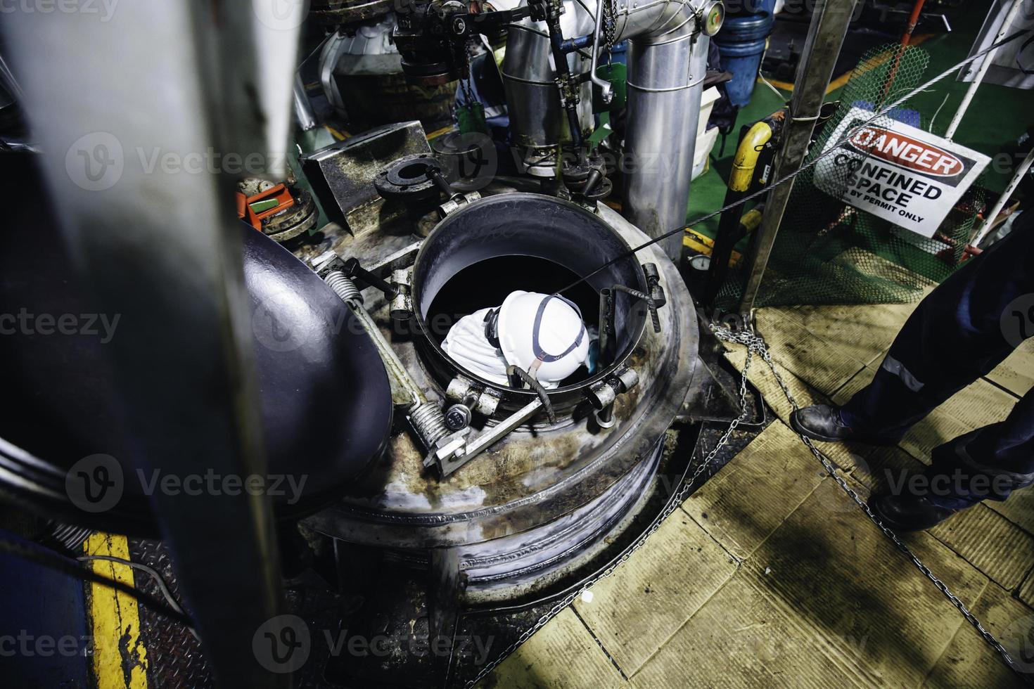 vista superior trabajador masculino sube las escaleras hacia el espacio confinado del área de grasa química de carbono del tanque. foto