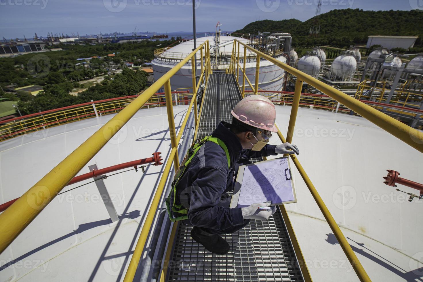 Male worker inspection visual roof storage tank oil background city. photo