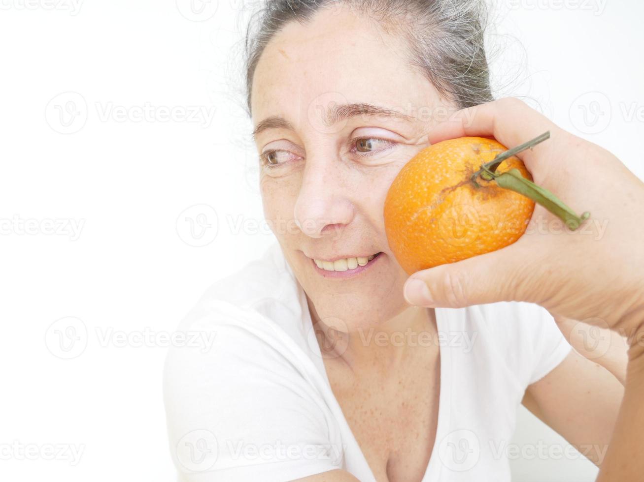 Forty nine year old woman in a white T-Shirt against a white background with an orange photo
