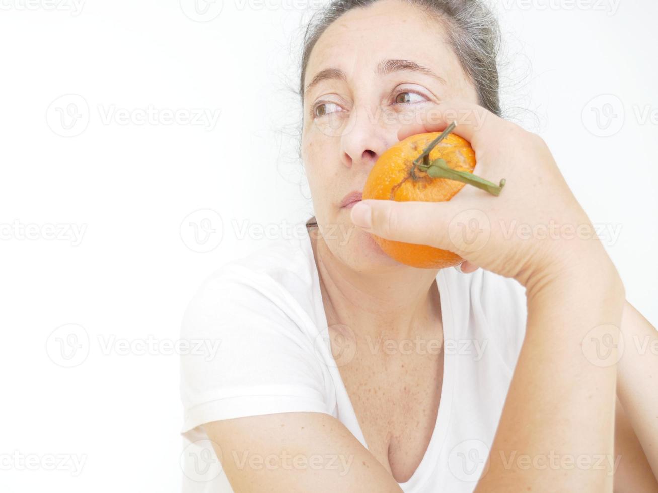 Forty nine year old woman in a white T-Shirt against a white background with an orange photo