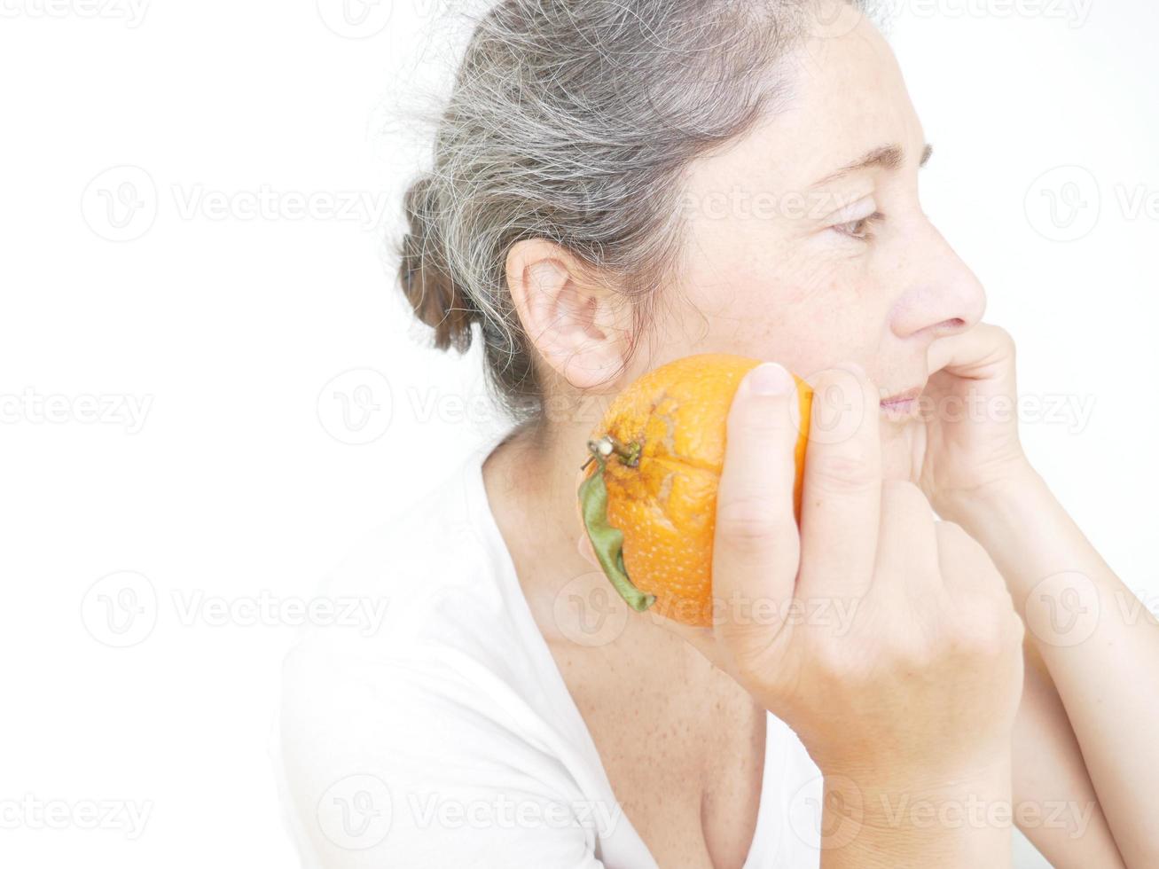 Forty nine year old woman in a white T-Shirt against a white background with an orange photo