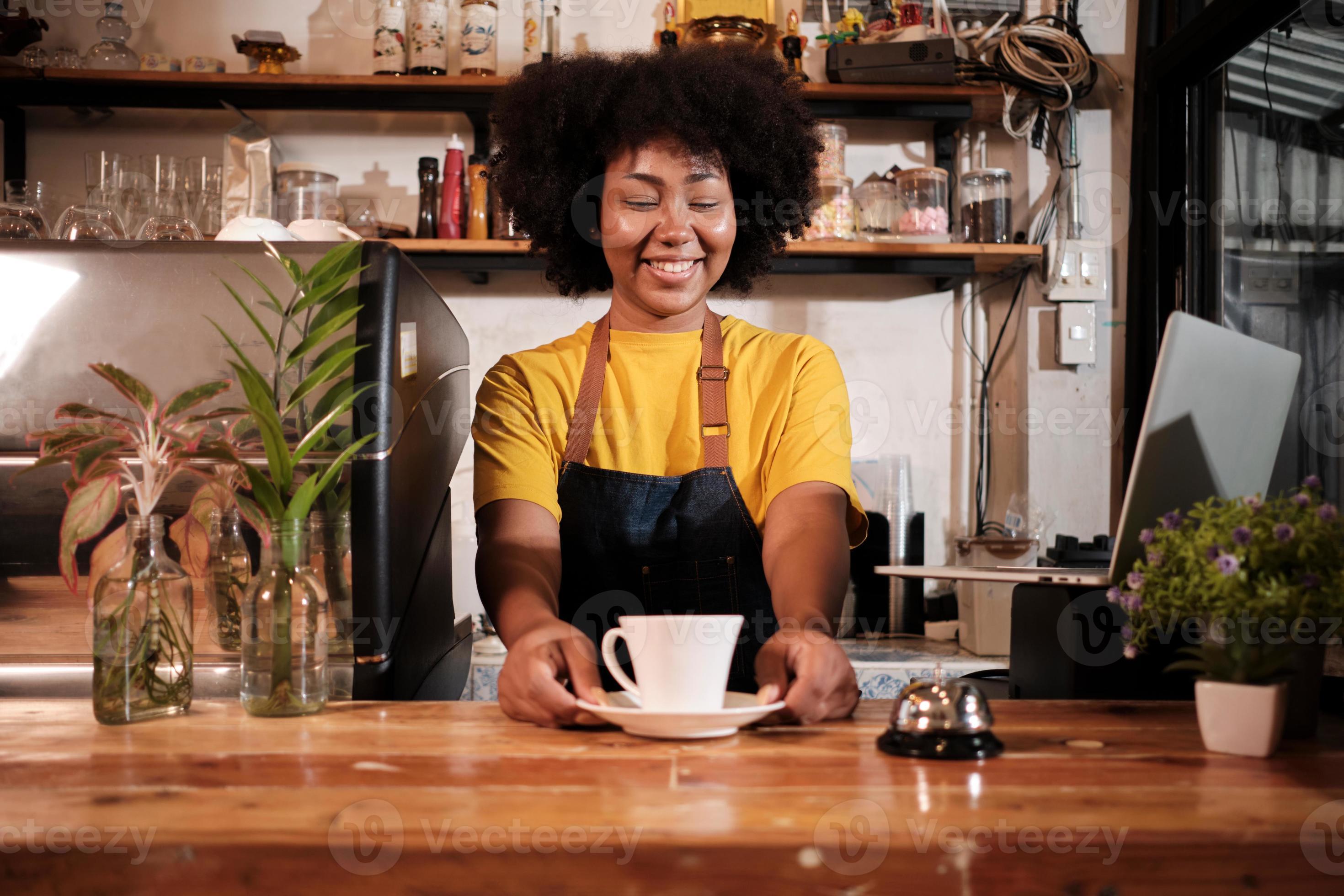 African American female barista offers cup of coffee to customer with
