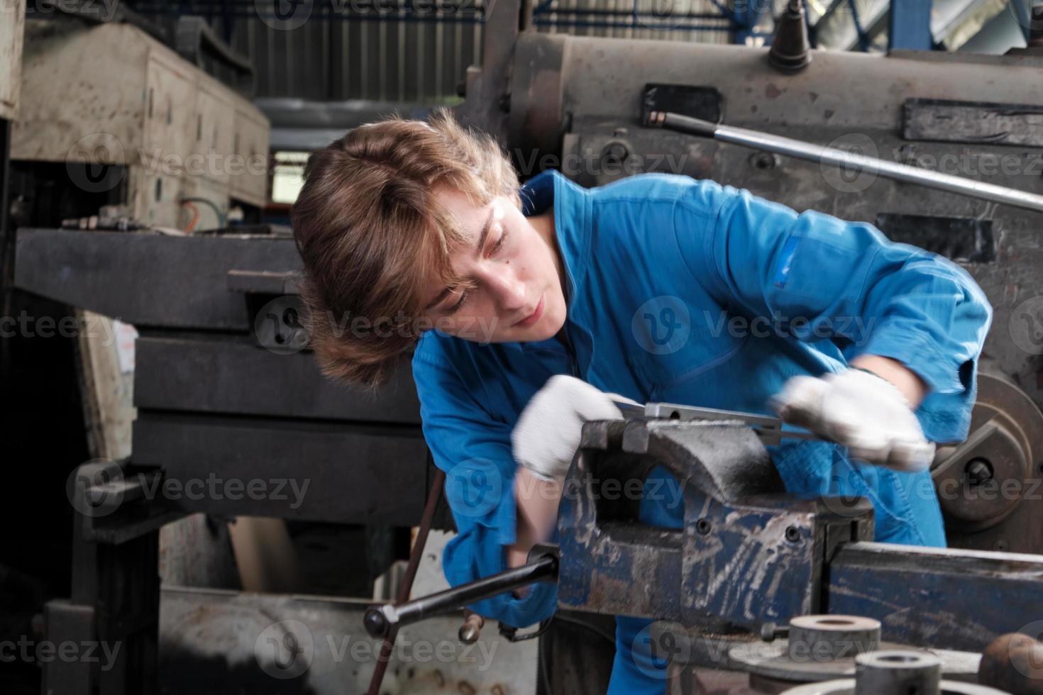One professional young female industry engineer worker works in a safety uniform with metalwork precision tools, mechanical lathe machines, and spare parts workshop in the steel manufacturing factory. photo