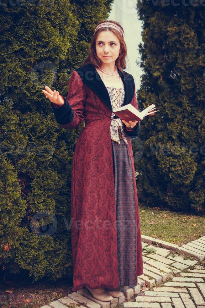 Portrait of brunette woman dressed in historical Baroque clothes  reading book, outdoors photo