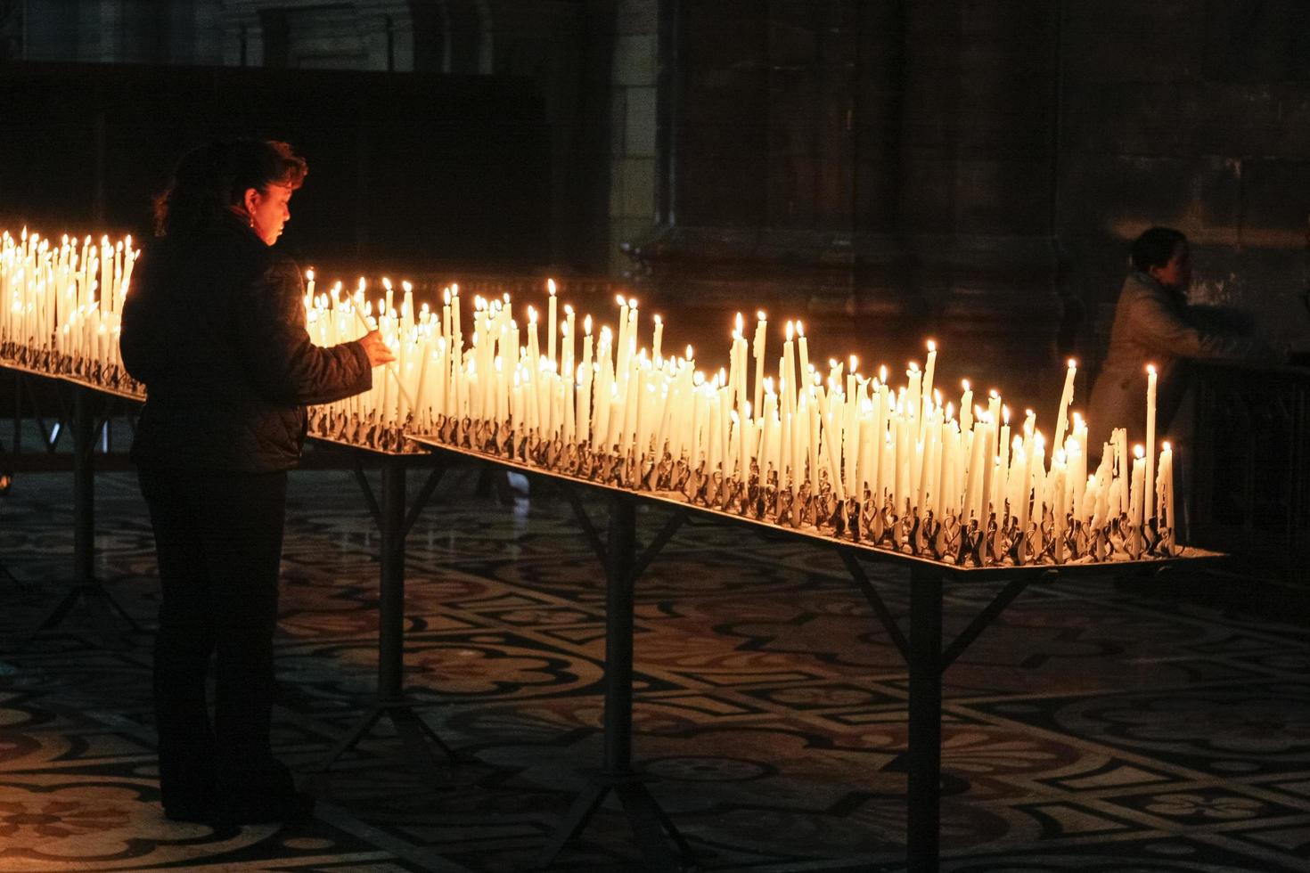 Burning candles in the Duomo Cathedral in Milan Italy on February 23, 2008. Two unidentified people photo