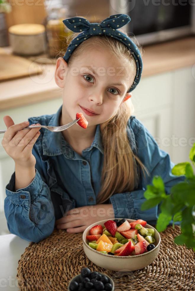 linda niña come ensalada de frutas foto
