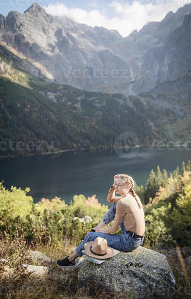 Young woman on a hiking trip sitting on a rock photo