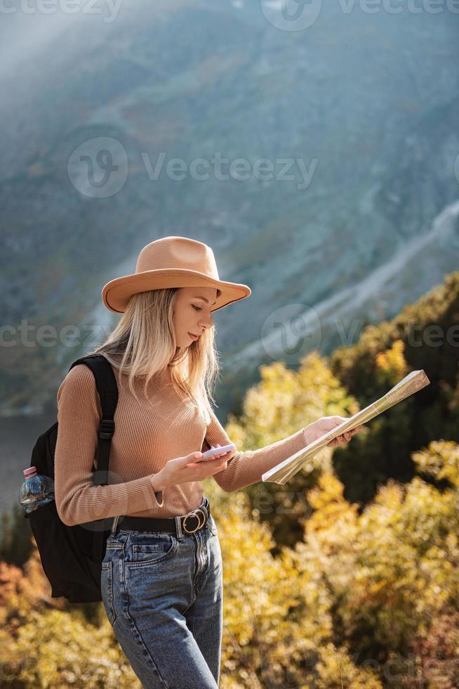 pasión por los viajes y concepto de viaje. chica viajera elegante con sombrero mirando el mapa, explorando bosques. foto