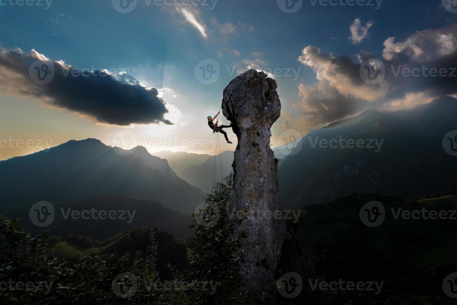 Double rope rappelling of a climber from the tip of a rock in a fairytale landscape photo