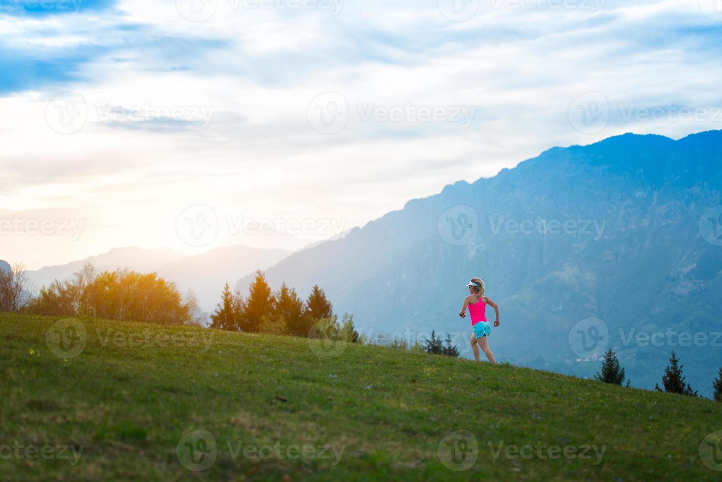 Blonde girl athlete runs in the mountains photo