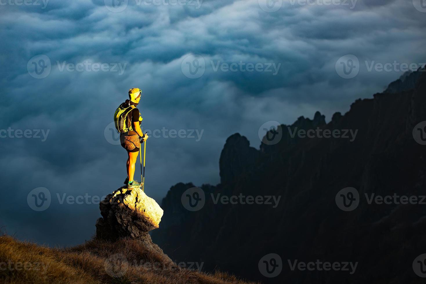 Fantastic sunset in mountains with hiker on a stone where he arr photo