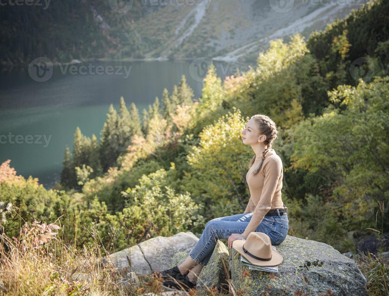 Young woman on a hiking trip sitting on a rock photo