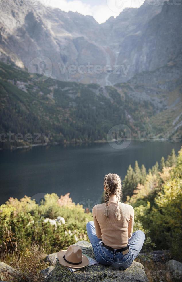 mujer joven en un viaje de senderismo sentado en una roca foto