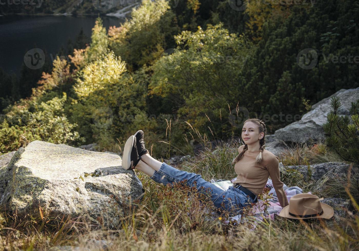 Young woman on a hiking trip sitting on a rock photo