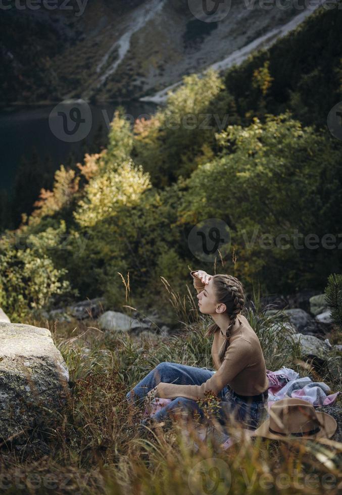 Young woman on a hiking trip sitting on a rock photo