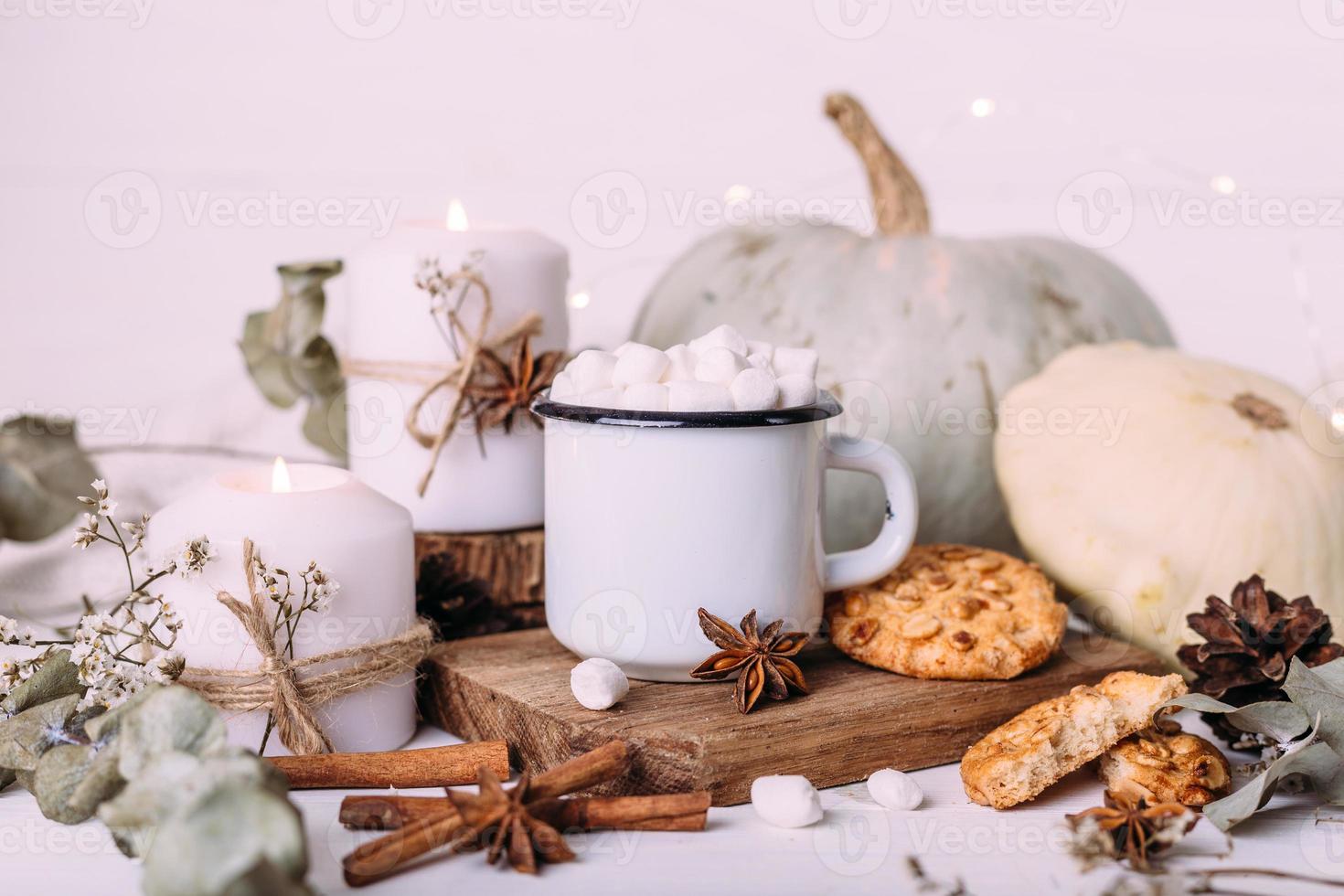 composición de otoño con cacao con malvaviscos, galletas, calabaza y velas foto