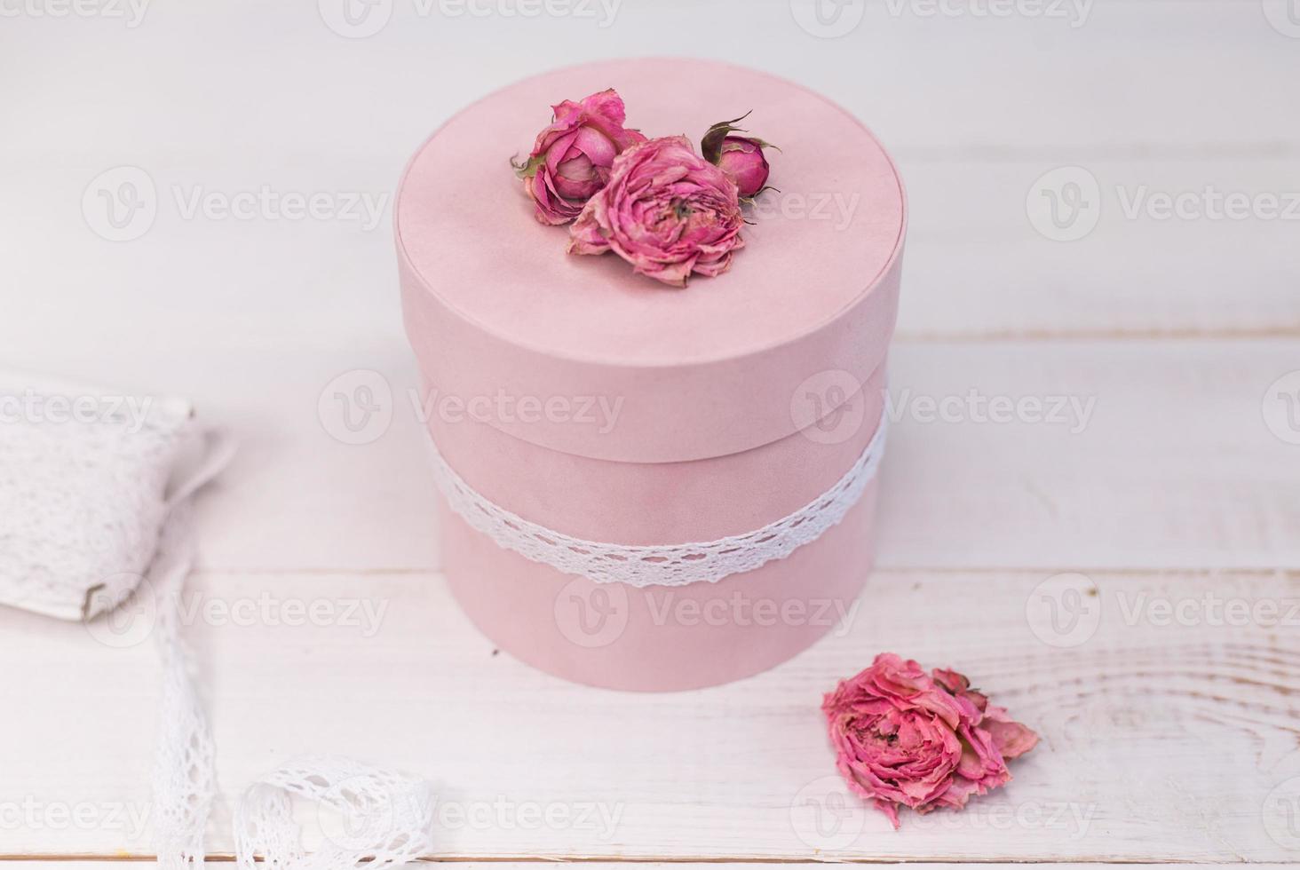 Beautiful pink round gift wrapping is decorated with narrowed roses. Romantic packaging concept photo