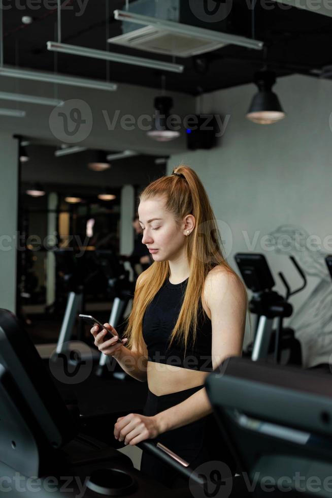 Happy athletic woman jogging on treadmills in a gym. photo